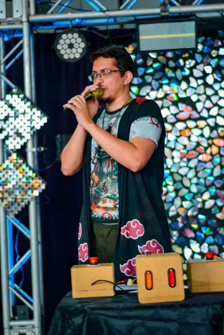 Vinny Manson apresentando um quiz no palco, com os botões de resposta dos competidores na mesa